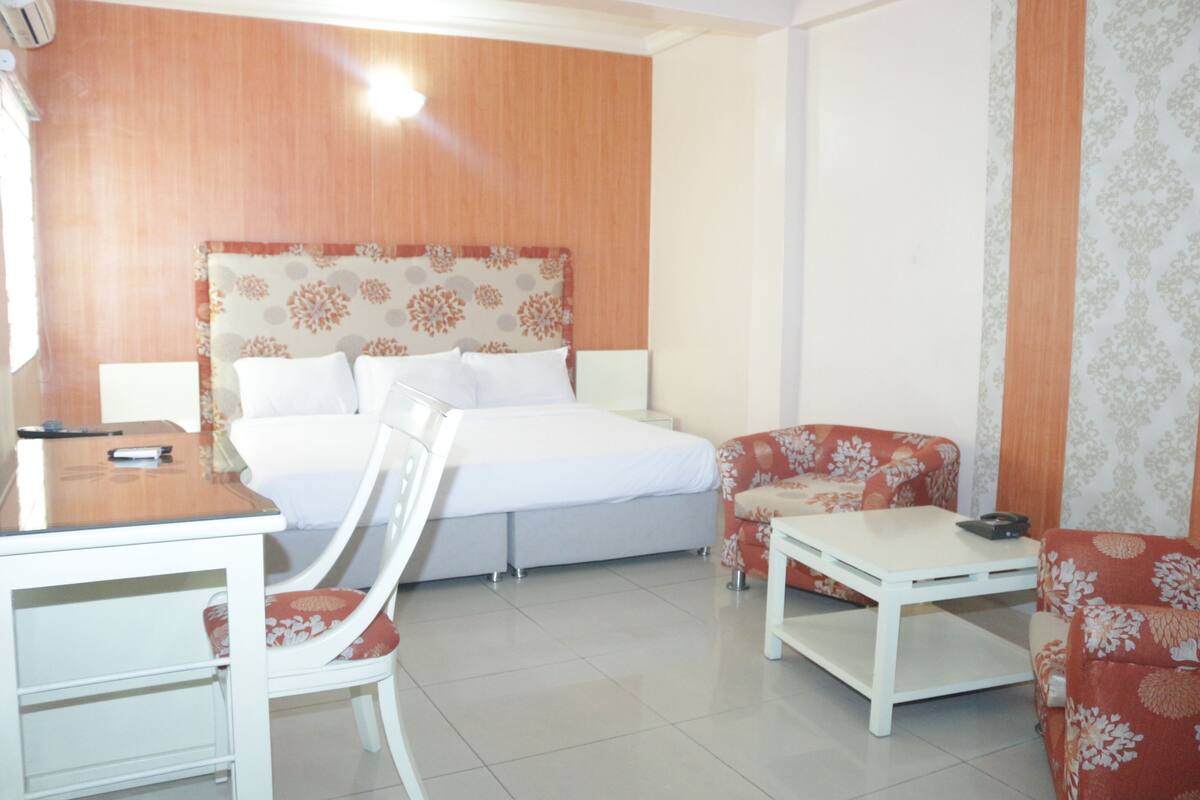 Een hotelkamer met een bed, een bureau, een stoel en een bank.
