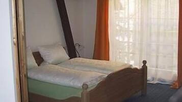 A bedroom with a wooden bed, a cross on the wall, and a chandelier.