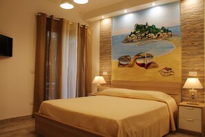 A hotel room with a bed, two bedside tables with lamps, a painting of a beach scene on the wall, and a curtain on the window. - B&B My Sicily (Giardini Naxos)