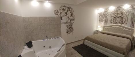 A bedroom with a large bed, a bathtub, and a wall mural.