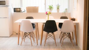 Una cocina moderna con electrodomésticos blancos, una mesa de comedor con cuatro sillas y lámparas colgantes.