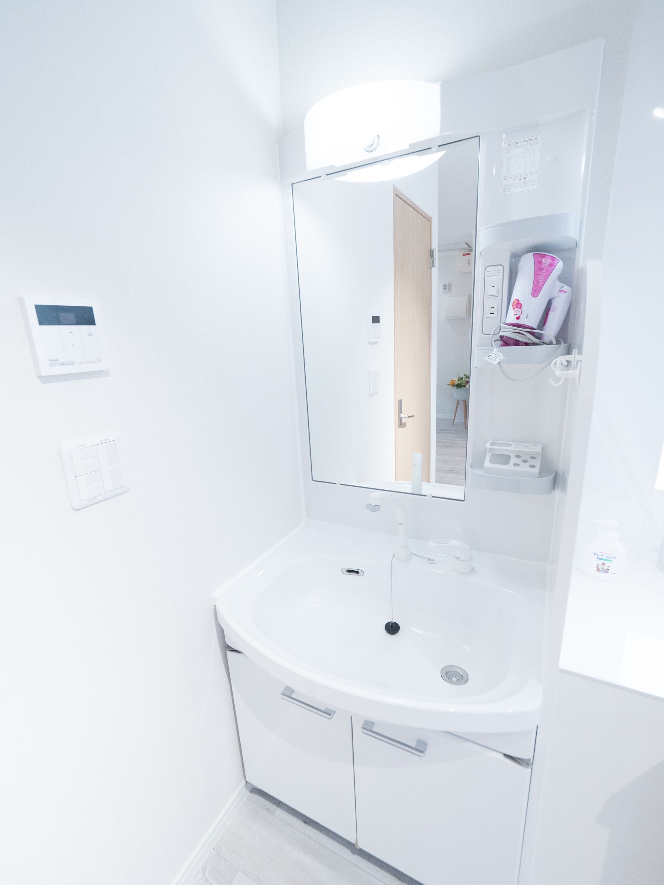 A modern bathroom with a white sink, a mirror, and a built-in heater.
