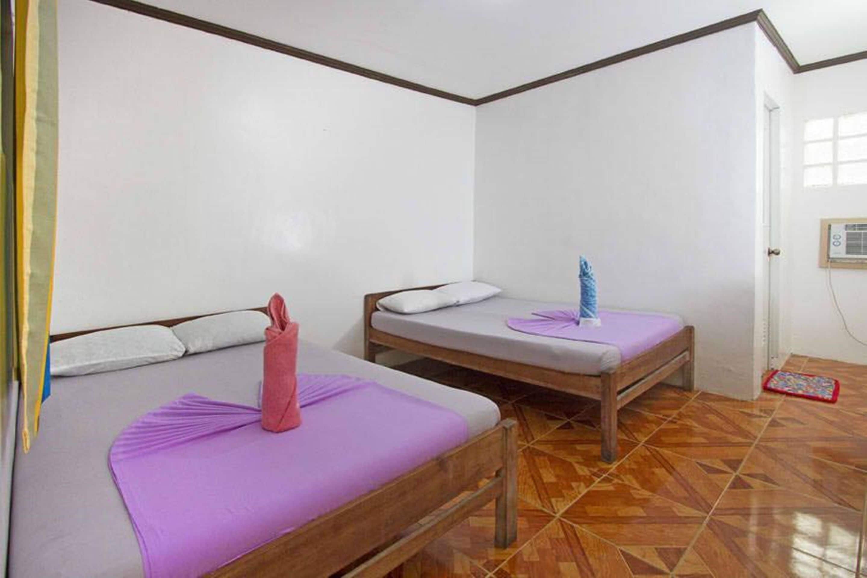 A room with two wooden beds, each with a pillow and a blanket.