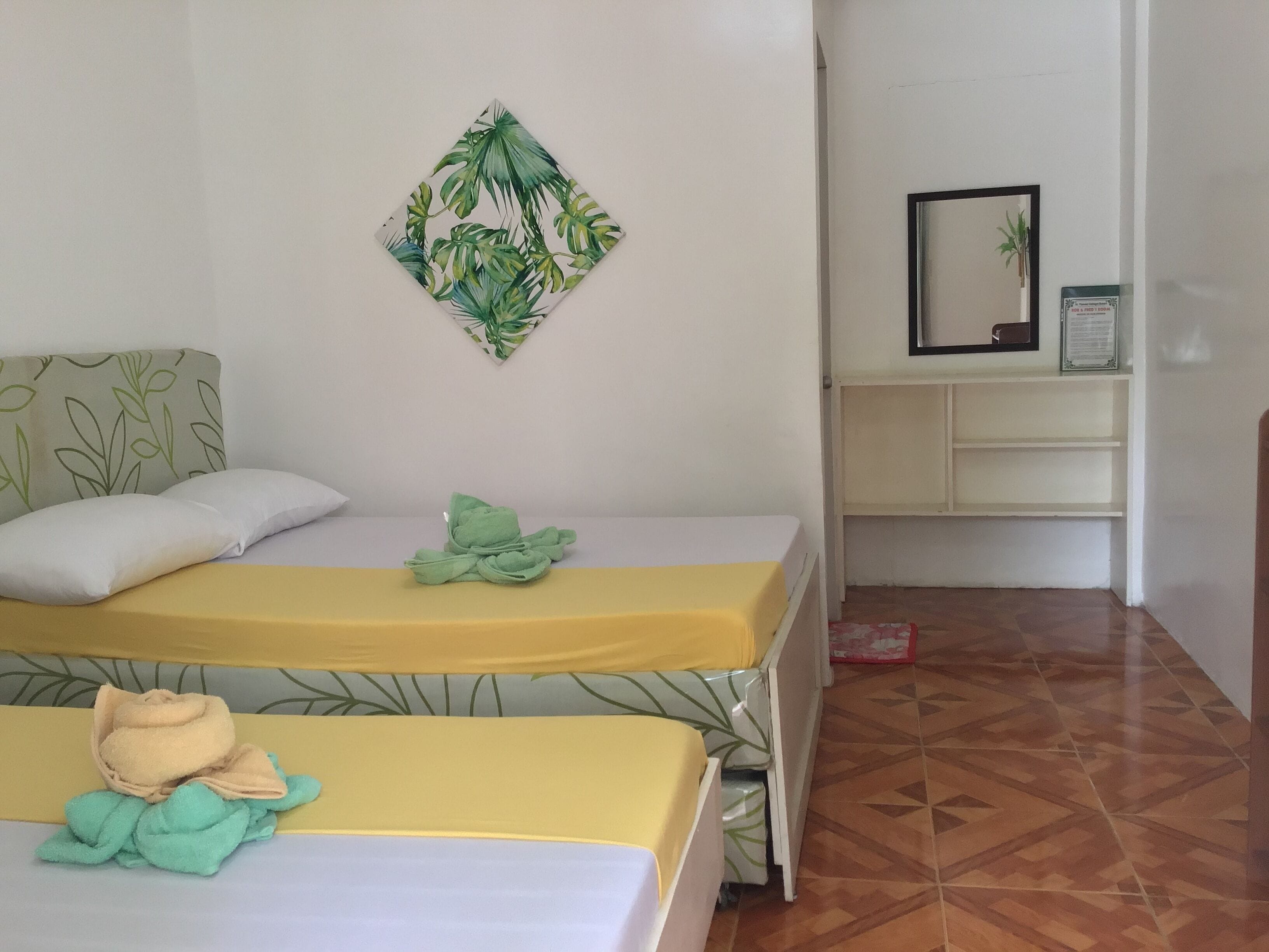 Una habitación con dos camas, un escritorio pequeño y un cuadro en la pared.