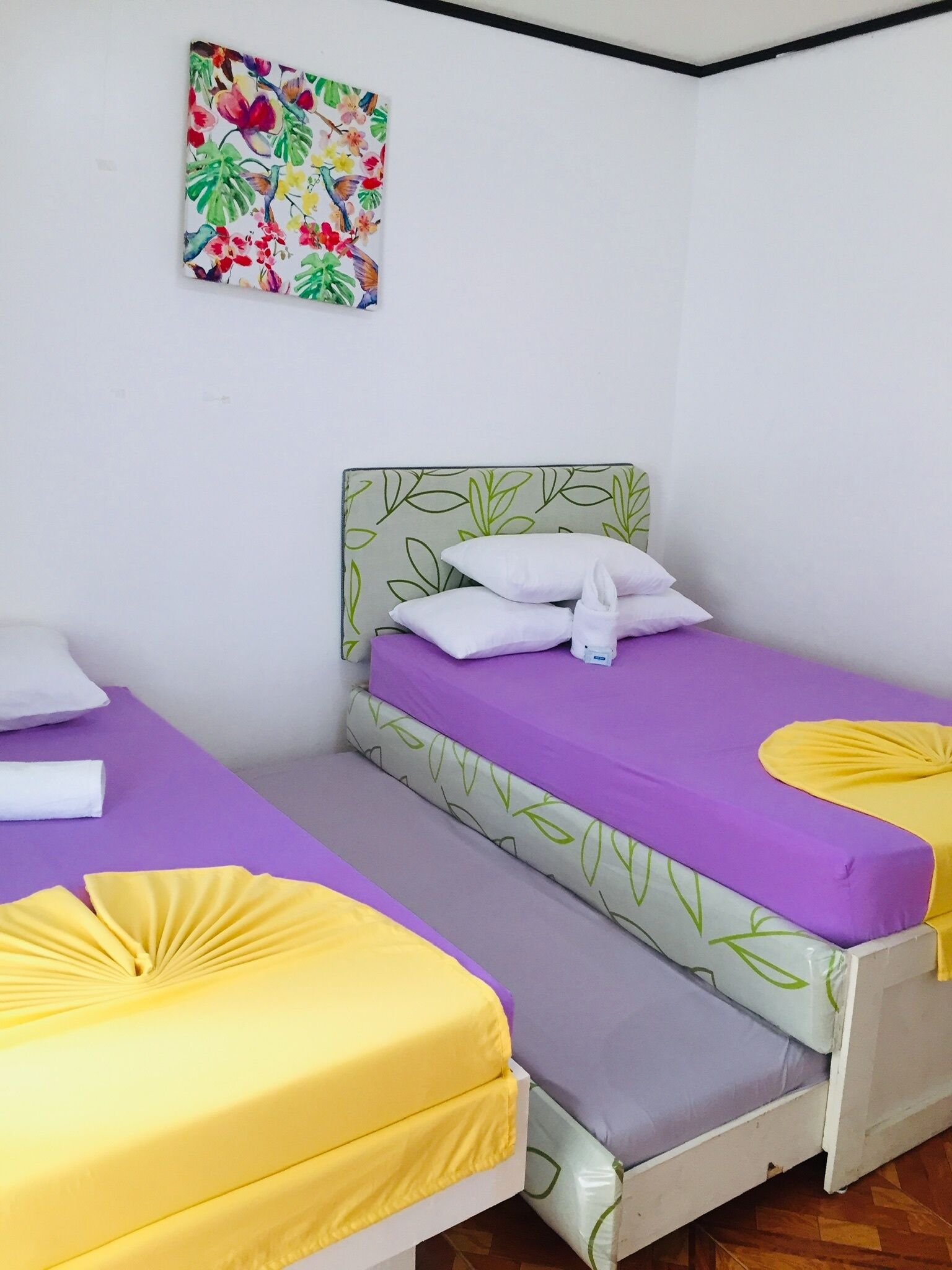 A small, single-bed room with a green leaf-patterned headboard and purple bedding.