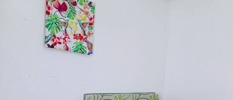 A small, single-bed room with a green leaf-patterned headboard and purple bedding.