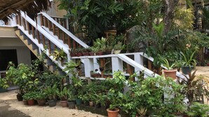 A staircase with white railings and bamboo balusters, surrounded by various potted plants. - Rob and Fred's Resort (Boracay Island)