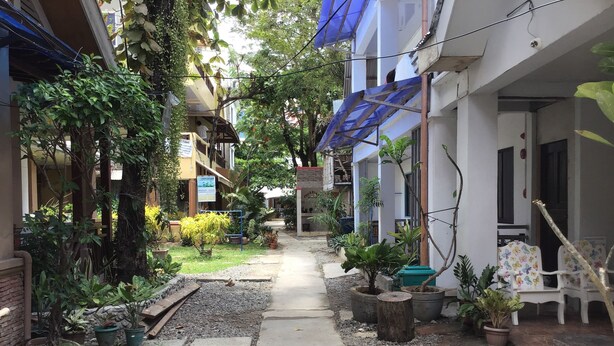 A narrow pathway flanked by potted plants and a row of white chairs with butterfly designs. - Rob and Fred's Resort (Boracay Island)