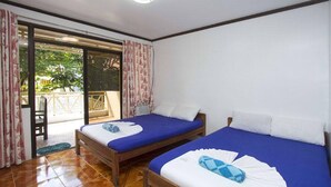 A room with two beds, a wooden floor, and a sliding glass door leading to an outdoor area. - Rob and Fred's Resort (Boracay Island)