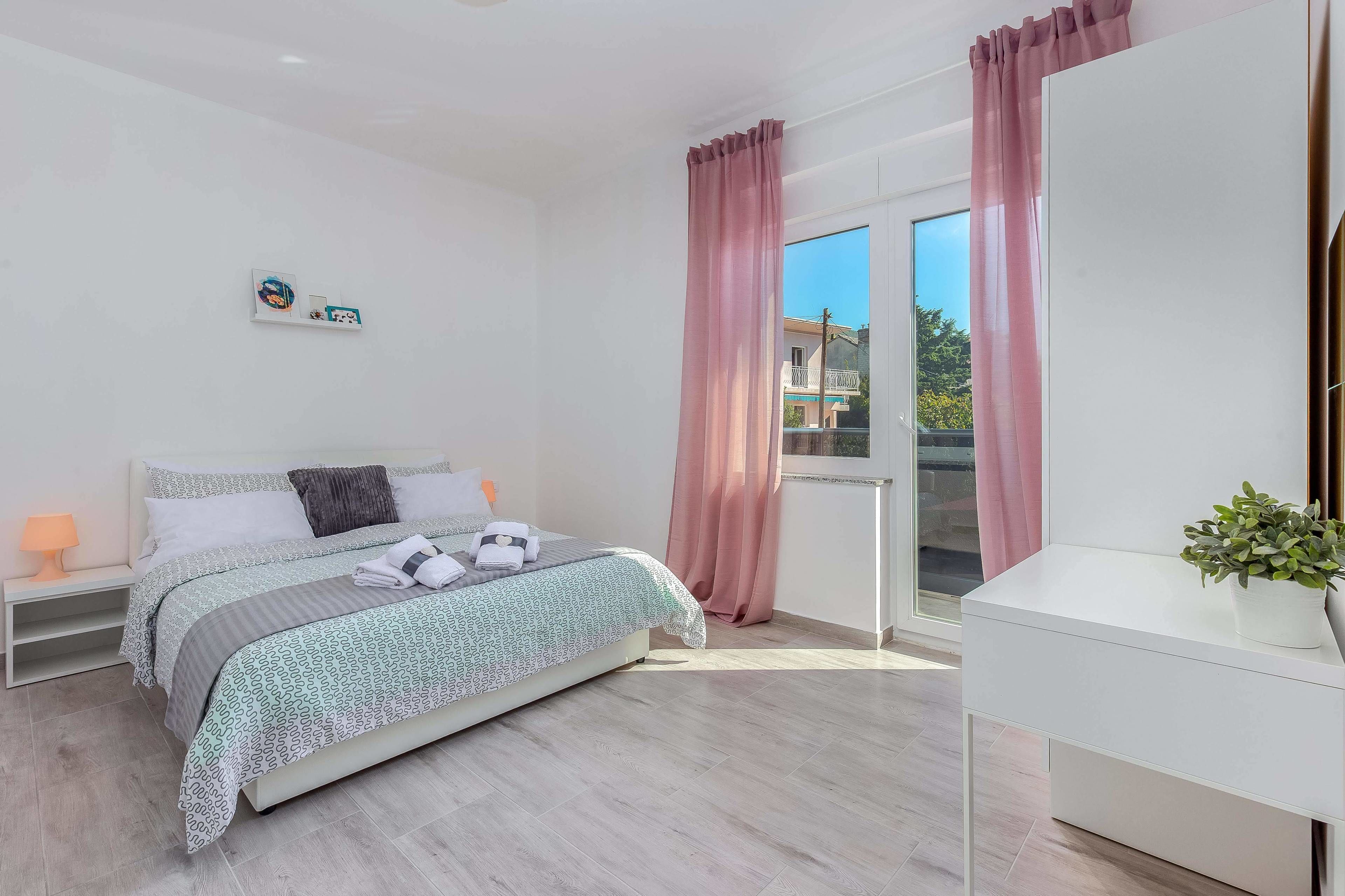 Een moderne slaapkamer met een bed, nachtkastje en een raam met gordijnen.