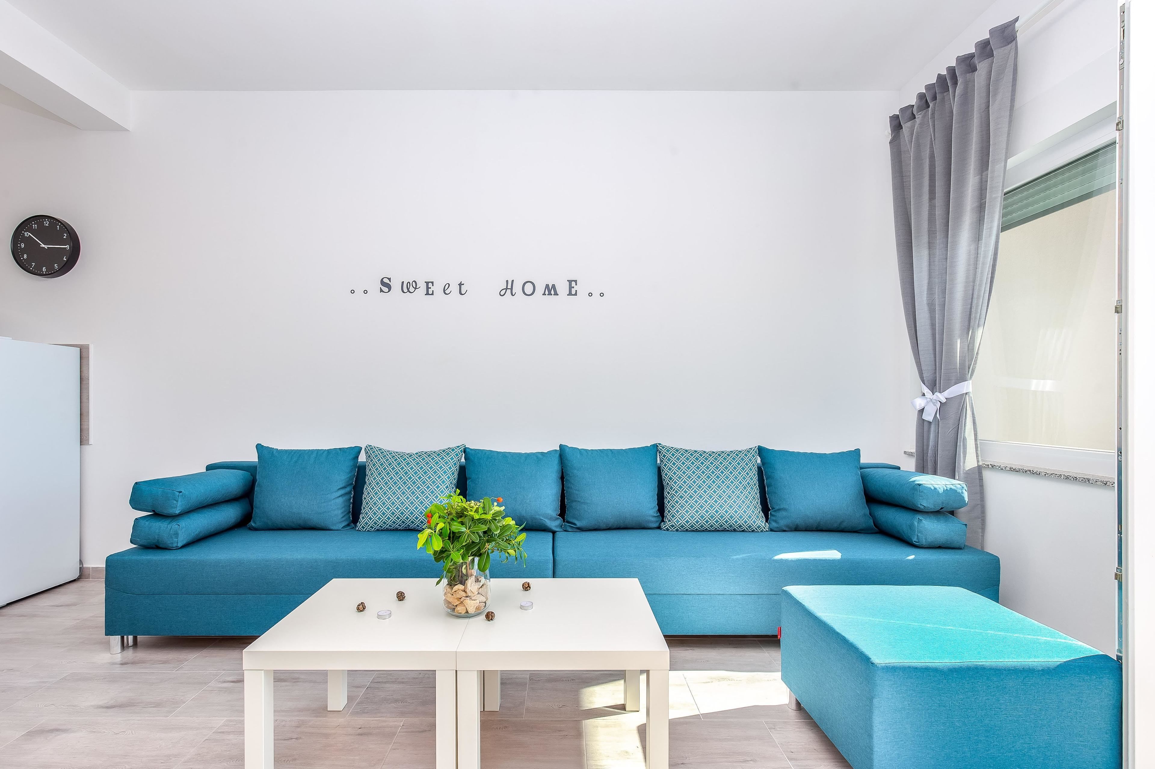 A modern living room with a blue sofa, a white coffee table, and a decorative plant.