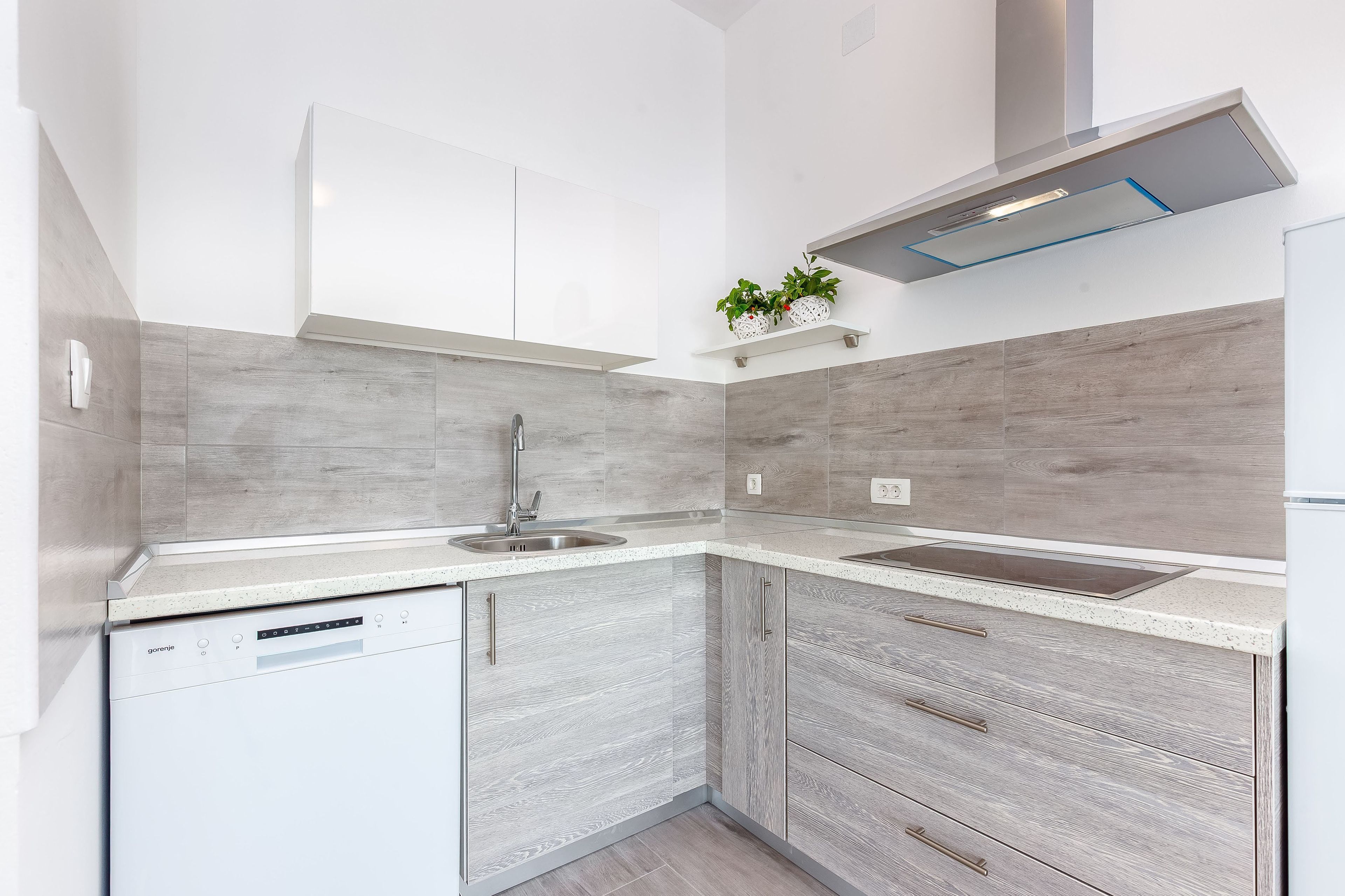 A modern kitchen with a dishwasher, sink, and a built-in oven.