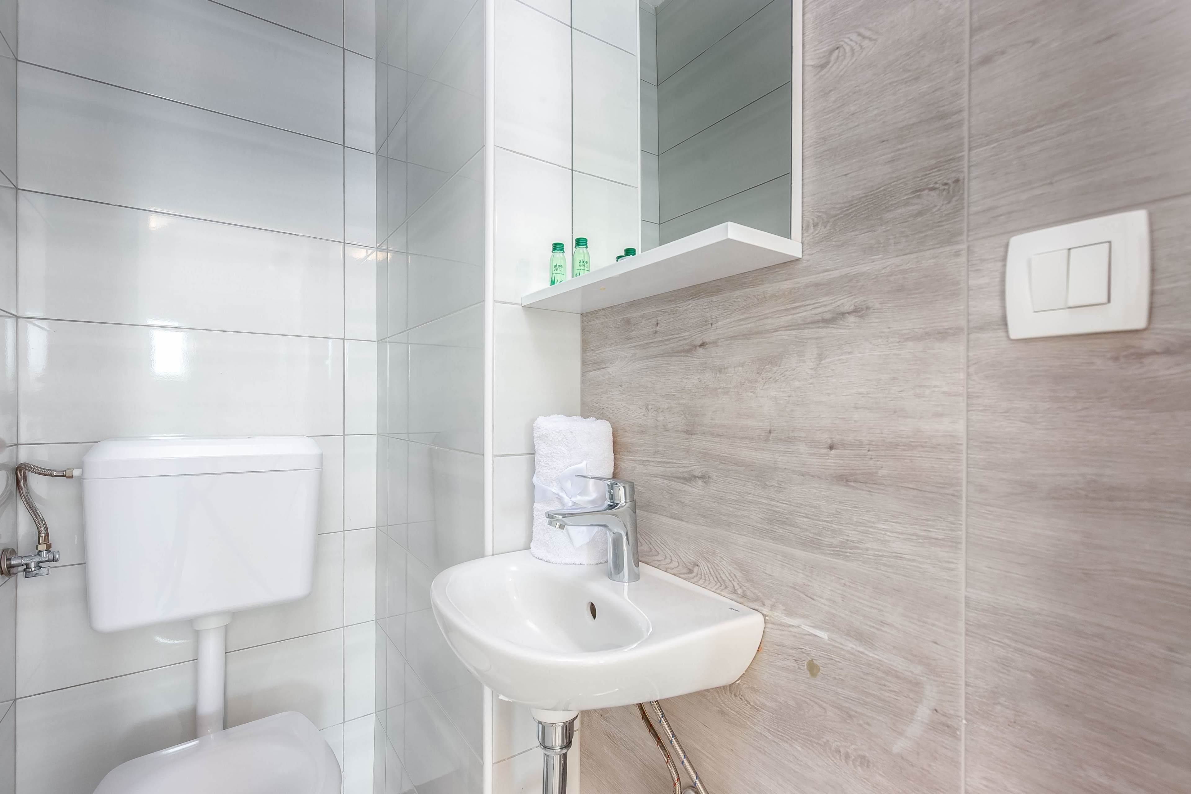 A bathroom with a white toilet, a white sink with a wooden backsplash, and a mirror above the sink.