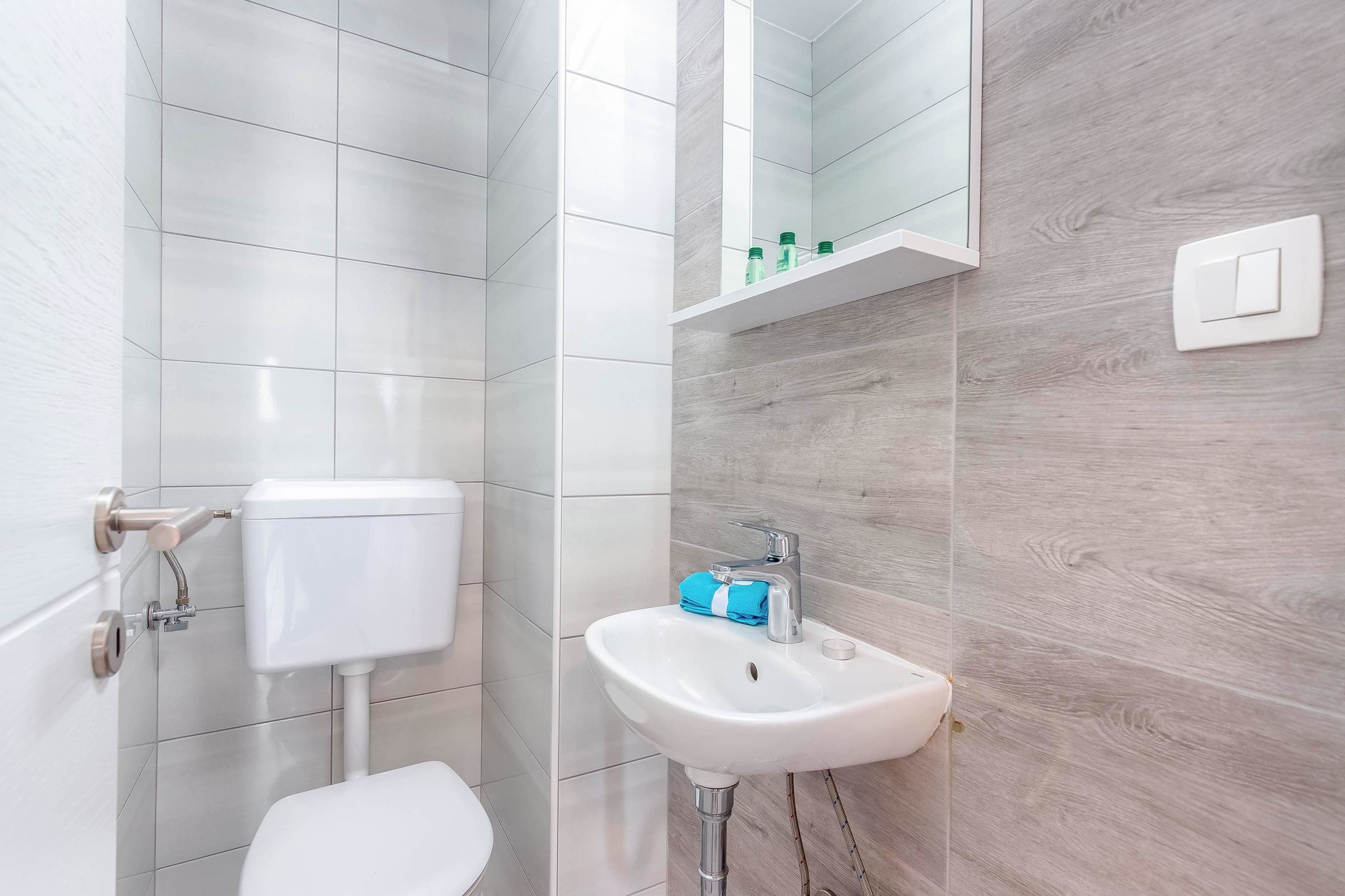 Une salle de bain moderne avec des toilettes, un lavabo et un miroir.