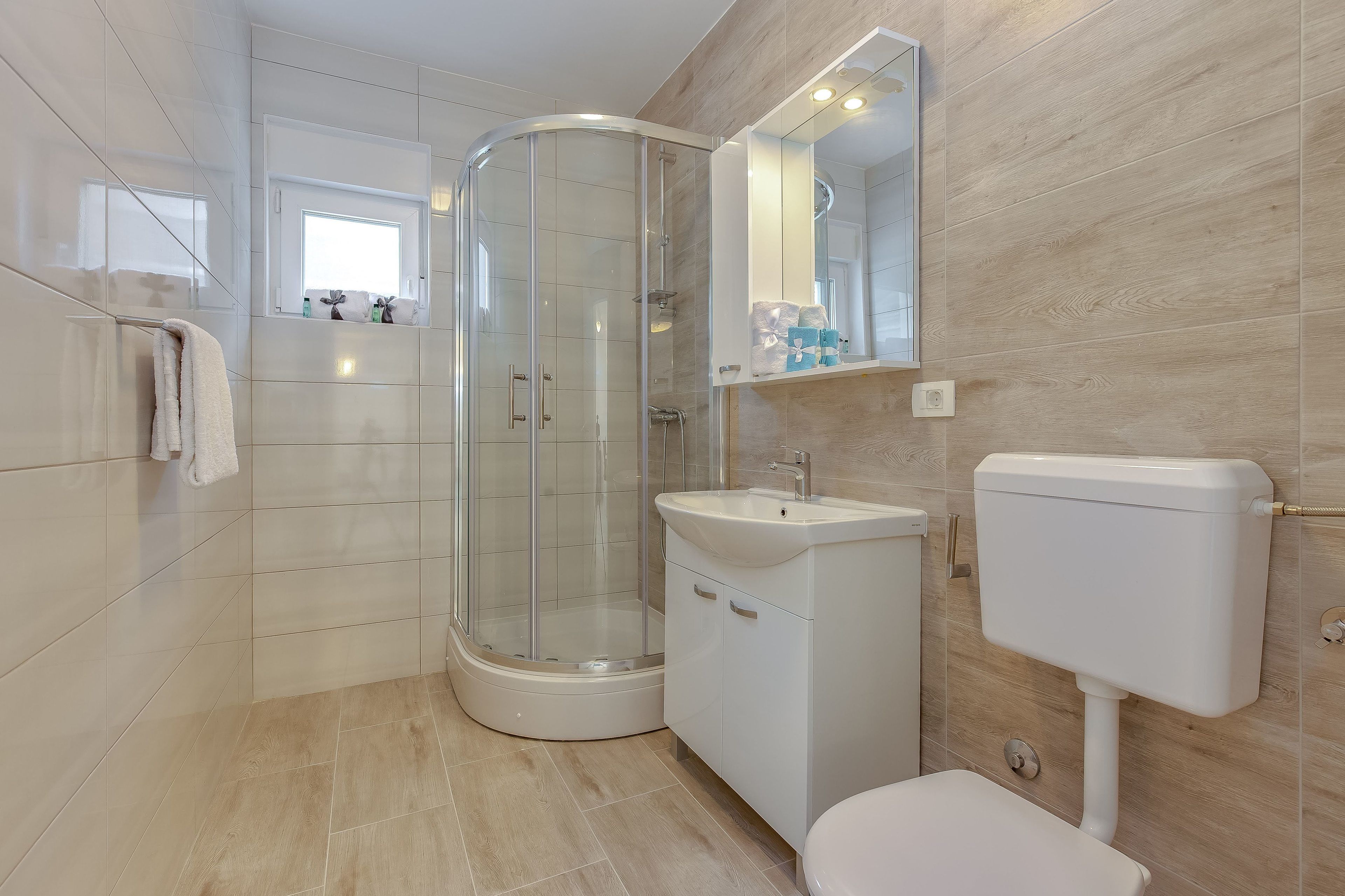 A modern bathroom with a glass-enclosed shower, a white sink, and a toilet.