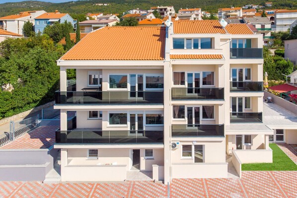 A multi-story residential building with balconies, a tiled roof, and a paved ground. - Villa Veronique (Crikvenica)