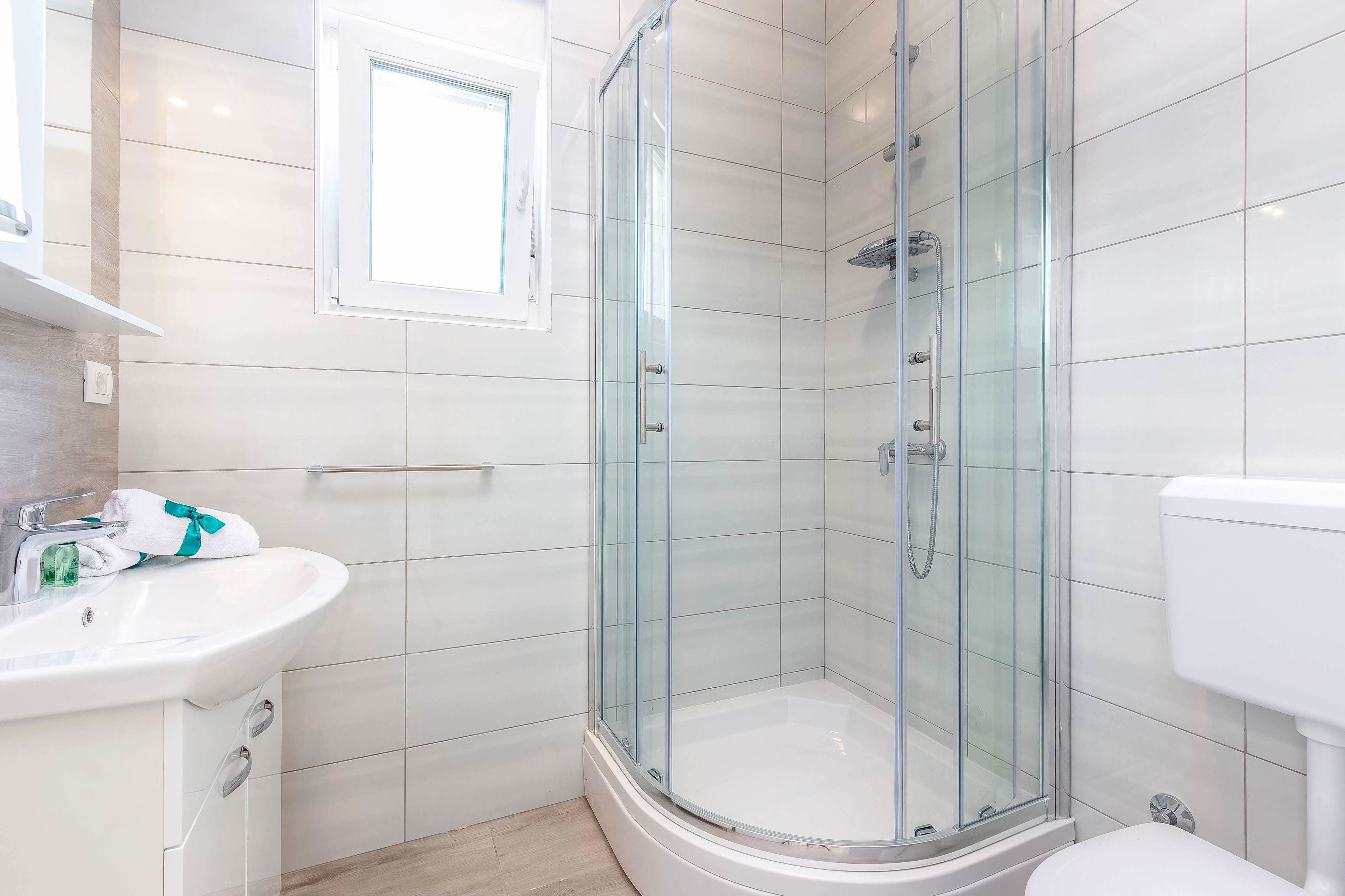 A modern bathroom with a glass-enclosed shower, a white sink, and a toilet.
