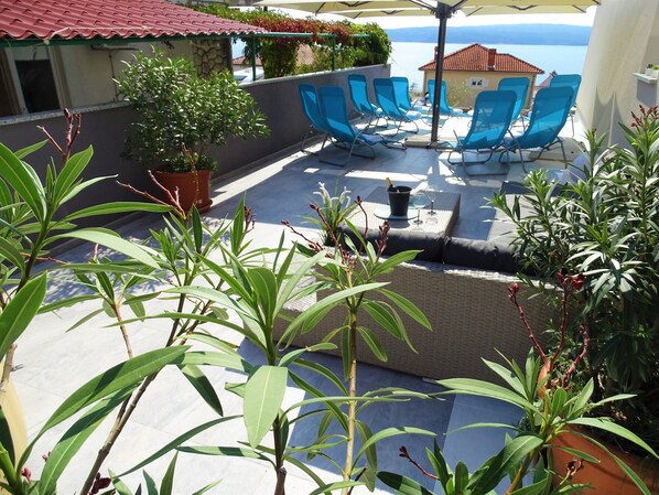 A terrace with outdoor seating, potted plants, and a view of the sea. - Villa Veronique (Crikvenica)