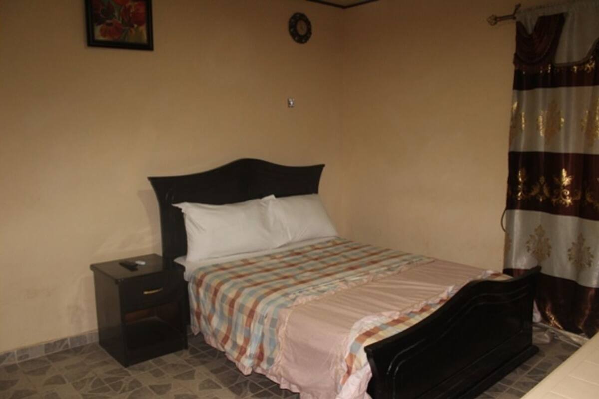 A bedroom with a bed, nightstand, and a wall clock.