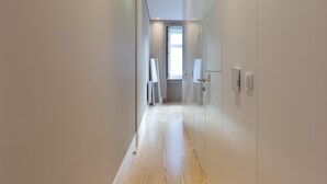 A hallway with wooden flooring, white walls, and a door leading to a room. - Porto and Clérigos Views by Porto City hosts (Porto)