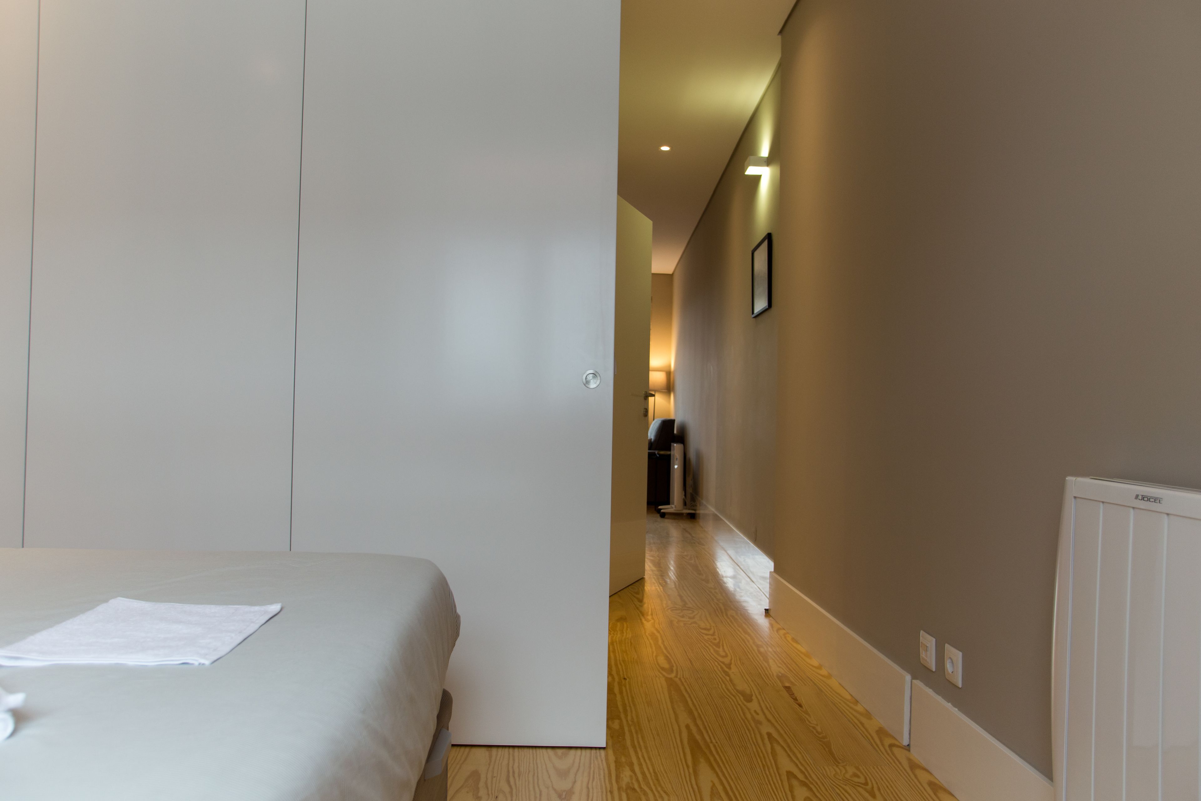 Un dormitorio con una cama, una puerta y un pasillo que lleva a un baño.