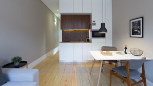 A modern kitchen with white cabinets, a wooden countertop, and a hanging pendant light. - Porto and Clérigos Views by Porto City hosts (Porto)