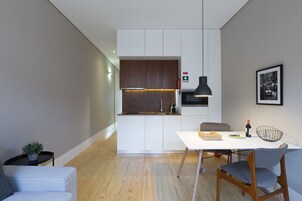 A modern kitchen with white cabinets, a wooden countertop, and a hanging pendant light.