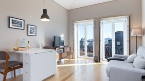 A modern living room with a sofa, a TV, and a dining area with a table and chairs. - Porto and Clérigos Views by Porto City hosts (Porto)