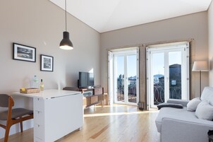 A modern living room with a sofa, a TV, and a dining area with a table and chairs.