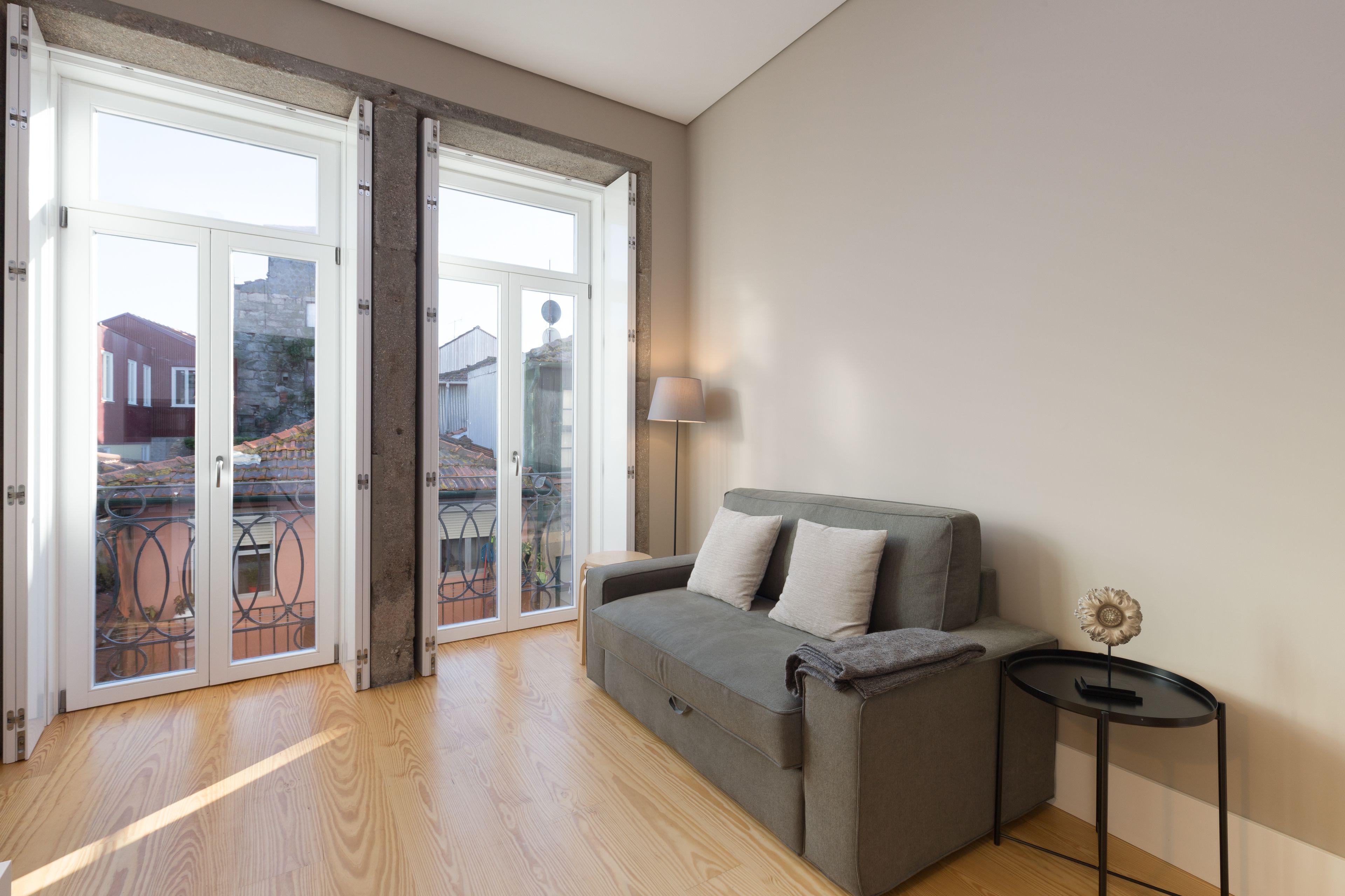 A modern living room with a grey sofa, a small round table, and a lamp.