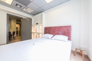 A hotel room with a bed, a small table, and a chair. - Athens Welcome Suites Apartments (Athens)