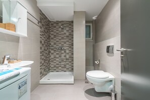 A modern bathroom with a shower, toilet, and sink. - Athens Welcome Suites Apartments (Athens)