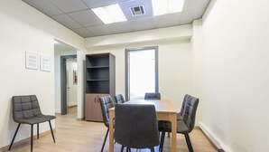 A modern meeting room with a wooden table, six chairs, and a bookshelf. - Athens Welcome Suites Apartments (Athens)
