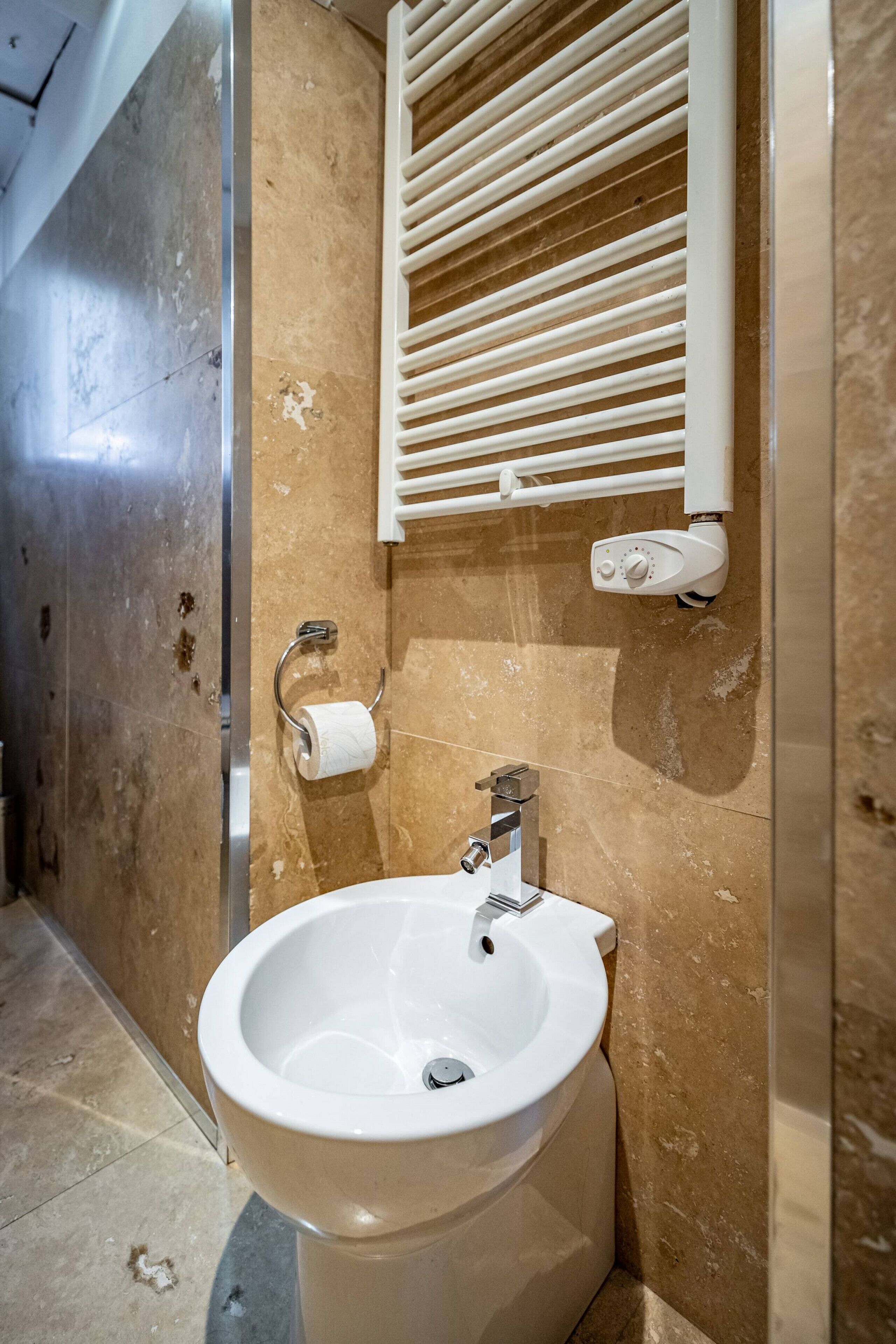A bathroom with a bidet, a towel rack, and a toilet paper holder.