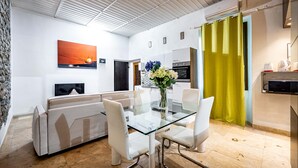 Una sala de estar moderna con una mesa de comedor de vidrio, sofás blancos y un cuadro grande en la pared.