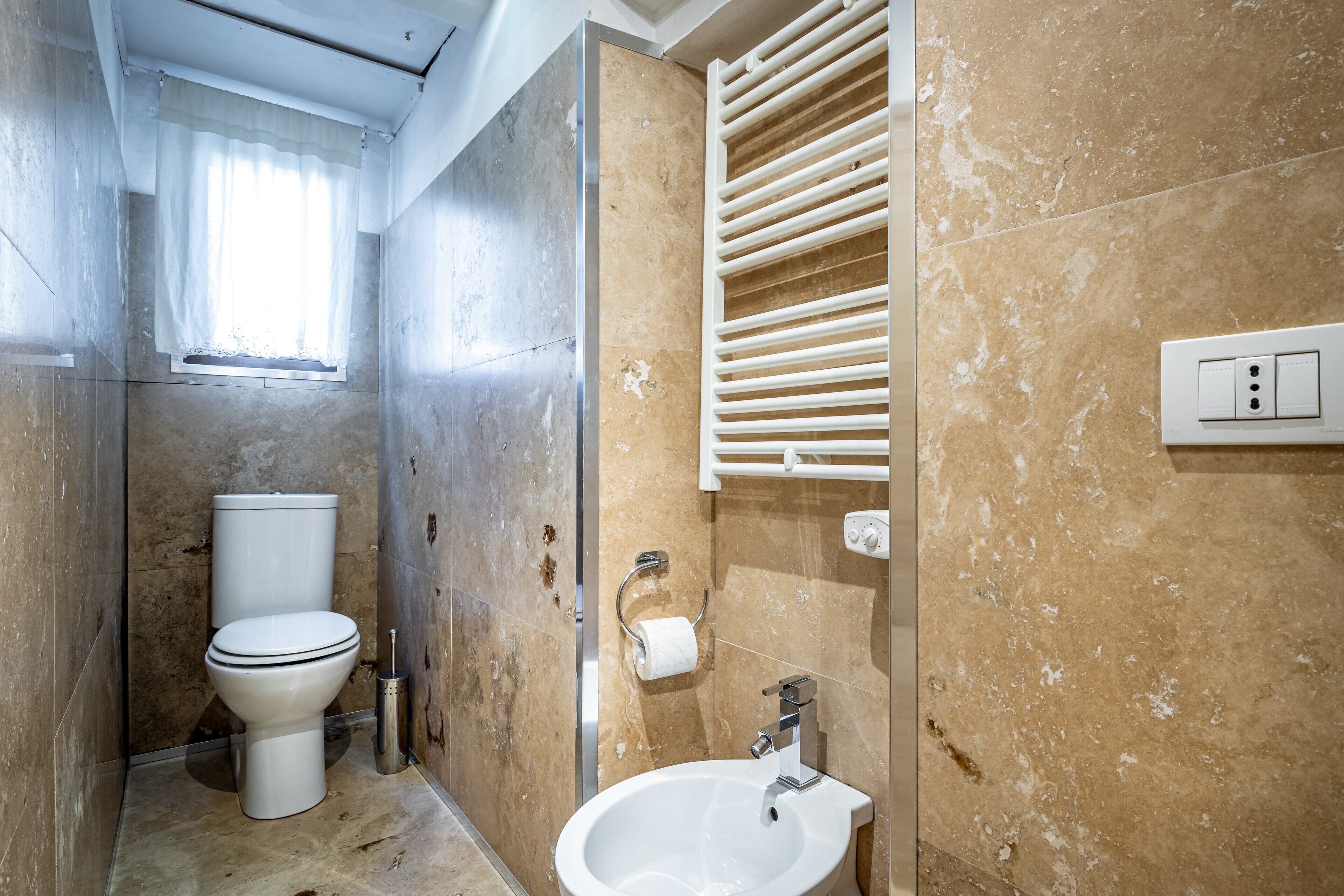 Une salle de bain comprenant des toilettes, un bidet, un lavabo et un porte-serviettes.