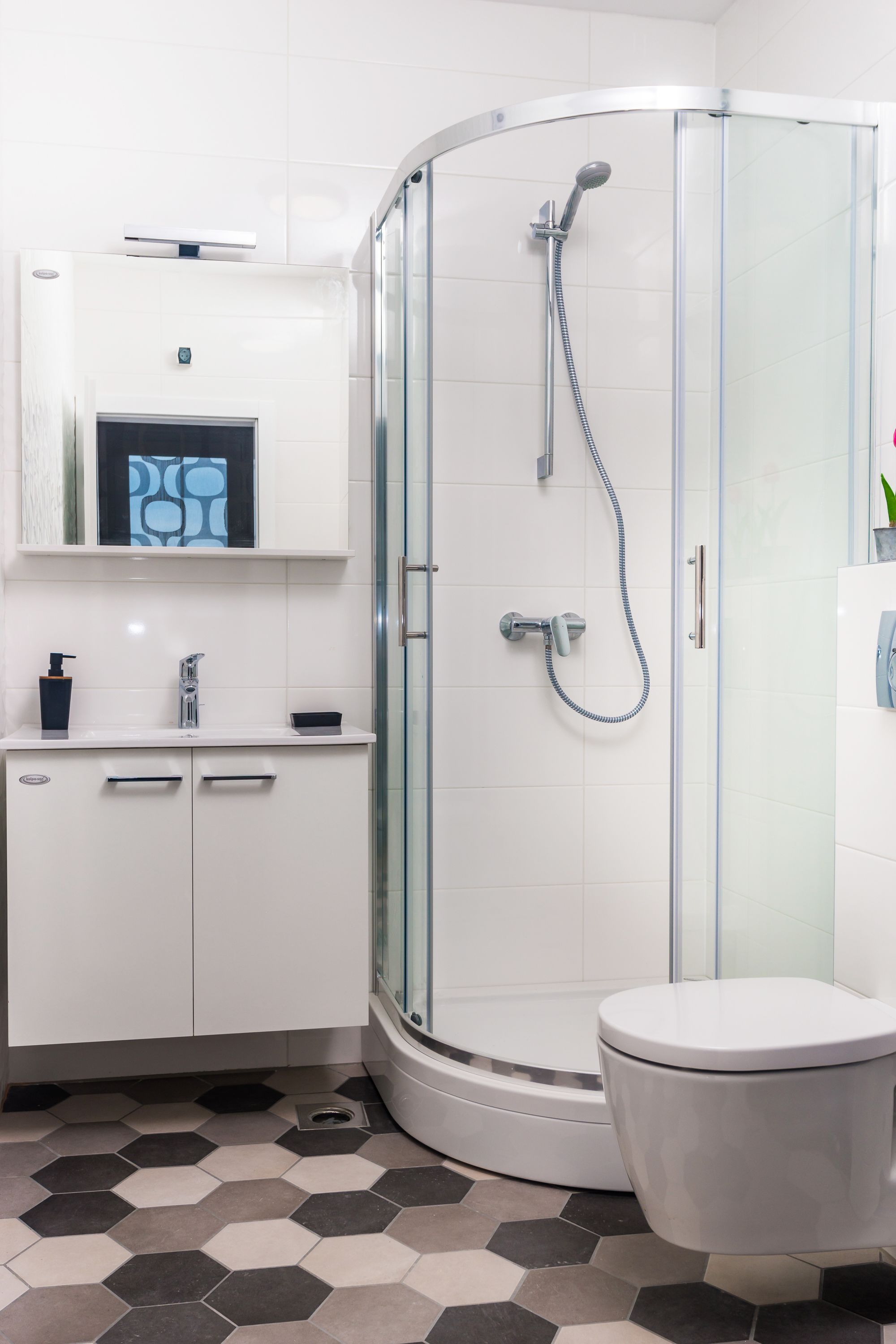 A modern bathroom with a glass-enclosed shower, a white toilet, and a sink with a mirror above.