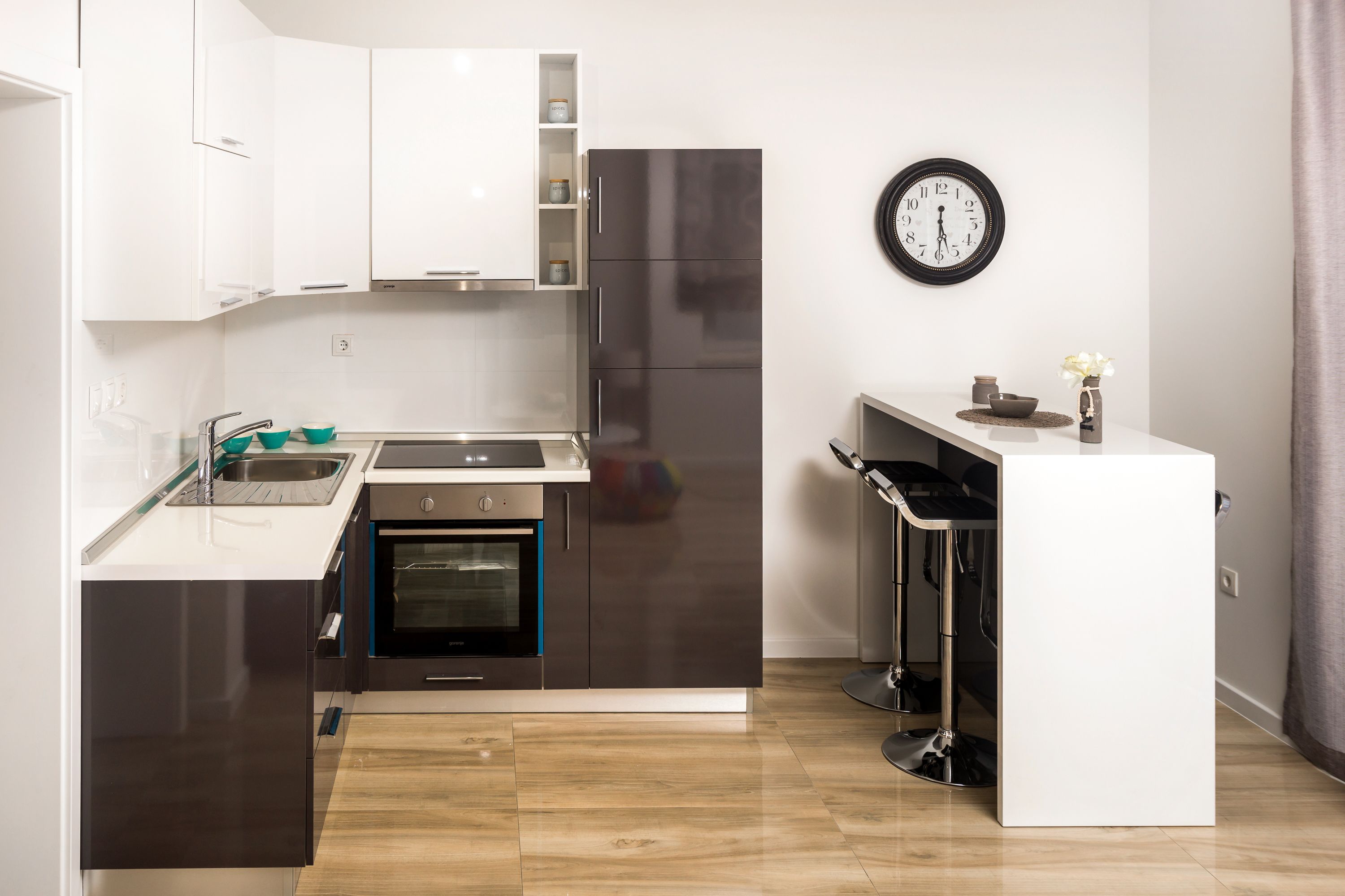 Una cucina moderna con mobili bianchi, un frigorifero in acciaio inossidabile e un forno integrato.