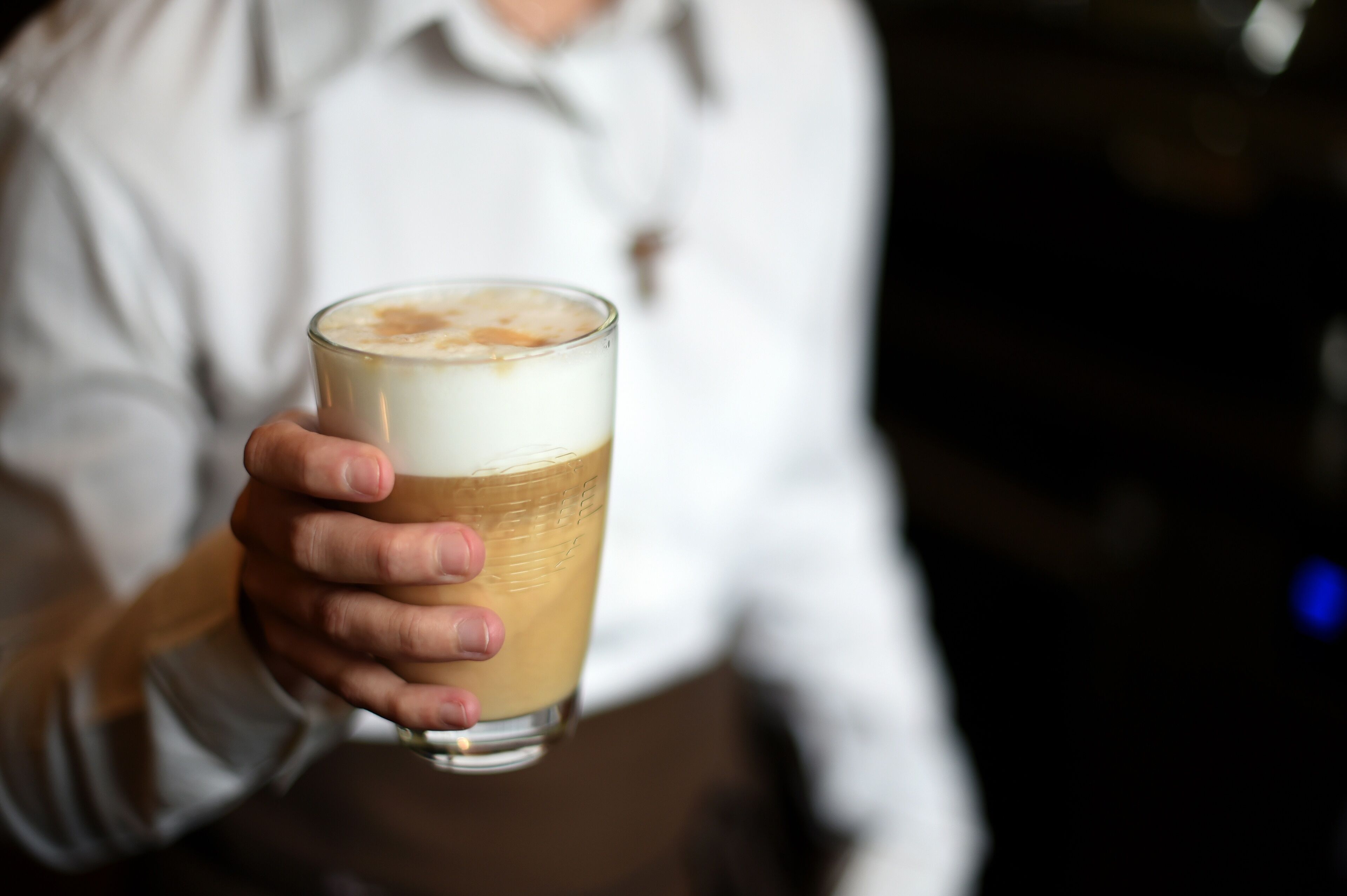 Una persona sosteniendo una taza de café con espuma.