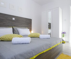 A modern bedroom with a large bed, a wardrobe, and a small table with a vase.