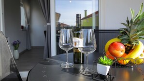 A table with two wine glasses, a bottle of wine, and a fruit bowl containing bananas, apples, and a pineapple. - Pool Apartments Privilege (Novalja)