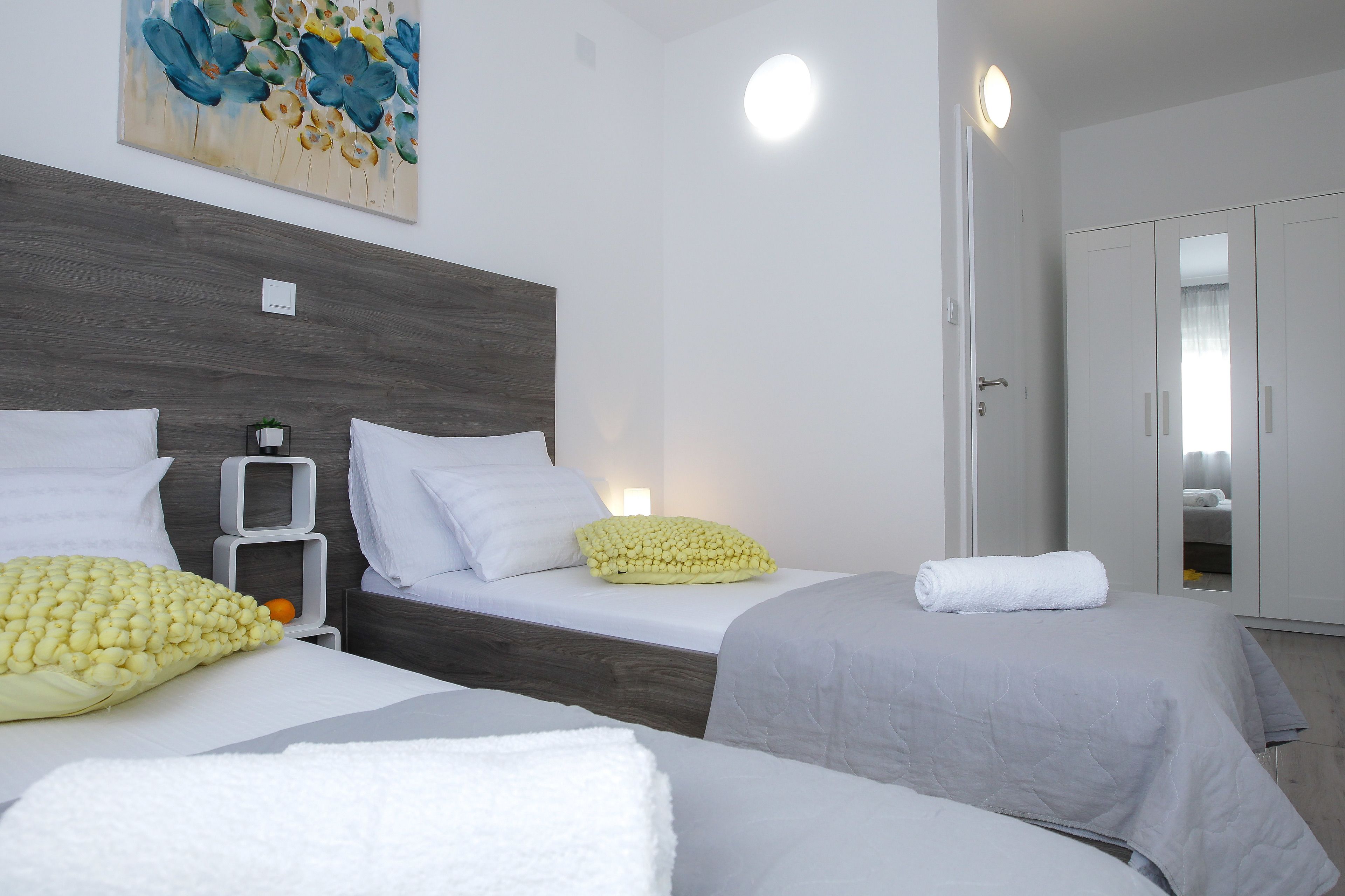 Habitación de hotel con dos camas, un cabecero de madera, un cuadro y un armario.