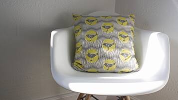 Une chaise blanche avec un coussin à motifs représentant des oiseaux jaunes et gris.