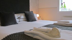 A hotel room with two beds, a window with a view of flowers, and a bedside table with a lamp. - The White House (Brighton)