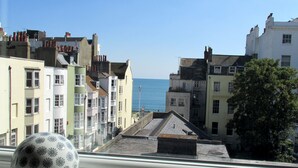 A coastal town with colorful buildings, a clear view of the sea, and a decorative ceramic sphere on a window sill. - The White House (Brighton)