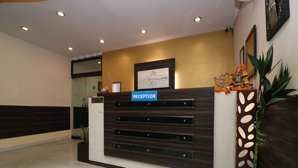 A reception desk with a sign reading "RECEPTION" and a sign above it that says "Check Out Time 12 Noon". - OYO 27718 Viva Destinations (Gurugram)