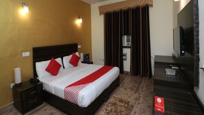 A hotel room with a bed, bedside table, lamp, ceiling fan, air conditioning unit, and a TV on a stand. - OYO 27718 Viva Destinations (Gurugram)