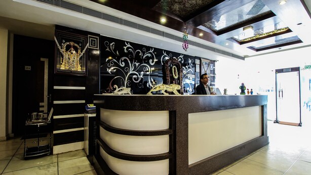 A reception desk with a decorative backdrop, a chandelier, and a tiled floor. - OYO 25125 Paharganj Dx (New Delhi)