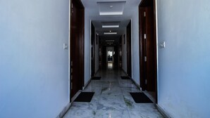 A long, narrow hallway with marble flooring and wooden doors on both sides. - OYO 25125 Paharganj Dx (New Delhi)