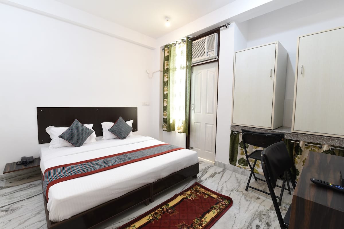 A neatly arranged bedroom with a bed, a desk, and a wardrobe.